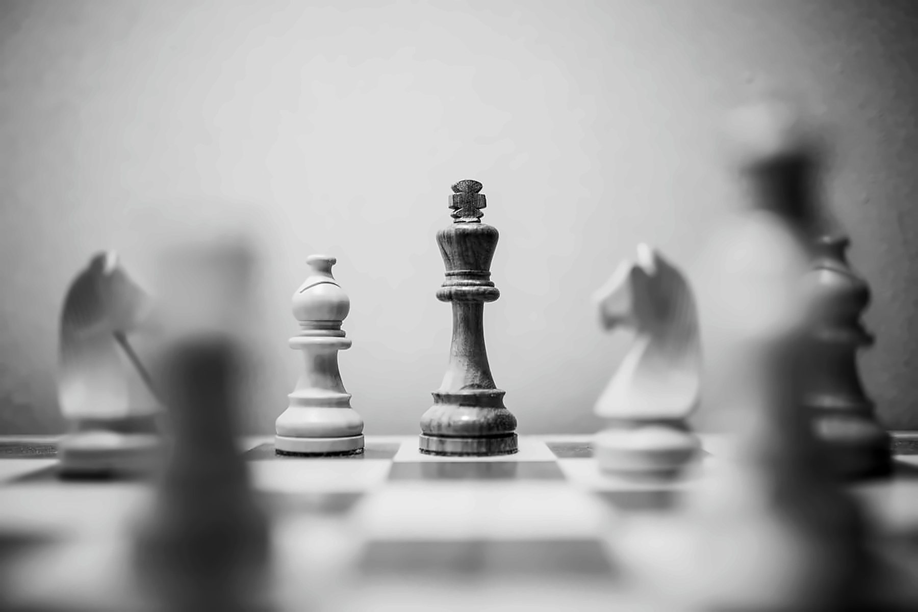 A chess king piece in focus, in black and white